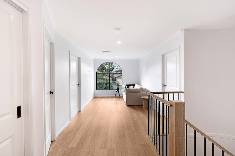 Discover the elegance of an upper storey addition crafted by Dura Group. This spacious, light-filled area features a sleek hallway with pristine white doors and a large, arched window that offers a scenic view. A comfortable sofa and stylish side table enhance the welcoming atmosphere. With over 27 years of construction experience, Dura Group specializes in home renovations and additions across Sydney. We prioritize time efficiency and budget-conscious planning without compromising on quality. Our family-owned company, led by Managing Director Mark, focuses on trust, transparency, and tailored building solutions. Experience seamless communication and a homeowner-first approach in every project. Whether you&rsquo;re considering a renovation or new addition, trust Dura Group to bring your vision to life. Contact us today to start your renovation journey and transform your living space with expert craftsmanship.