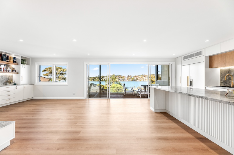 Experience the beauty of modern home design with Dura Group&rsquo;s exquisite open plan kitchen. This expansive space showcases luxurious hardwood flooring and elegant countertops that seamlessly blend style and functionality. Large sliding glass doors open to reveal breathtaking waterfront views, creating a perfect harmony between indoor and outdoor living. At Dura Group, based in Sydney, every renovation is custom-tailored to suit your unique needs, leveraging over 27 years of construction expertise. We prioritize time efficiency, budget-conscious planning, and consistent communication to ensure your project is completed without compromising quality. With a commitment to transparency and trust, we focus on delivering a homeowner-first approach that guarantees satisfaction. Whether you&rsquo;re considering a kitchen upgrade or a complete home renovation, Dura Group offers solutions that enhance your lifestyle. Transform your vision into reality with our expert craftsmanship and personalized service. Contact us today to start your renovation journey and experience the Dura Group difference!